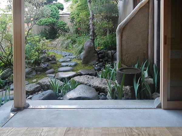 改修前の建物の壁土を使った袖垣と露地口から沢へ向かう伝い